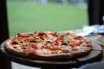 Pizza with olives on a wooden plate