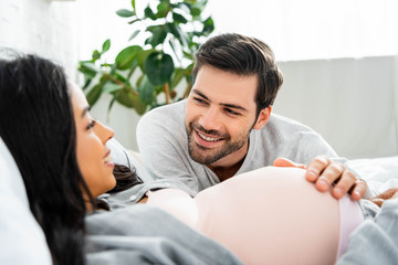 Fototapeta premium selective focus of handsome man hugging belly of his pregnant african american woman