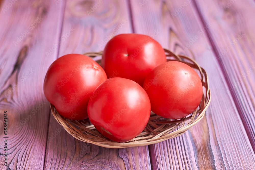 Wall mural fresh tomatoes on a pink wooden background.