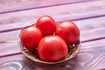Fresh tomatoes on a pink wooden background.