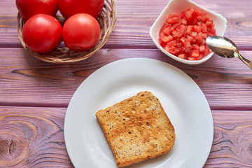 Toasted toasts and chopped tomatoes. Vegetarian bruschetta cooking with fresh tomatoes and pepper...