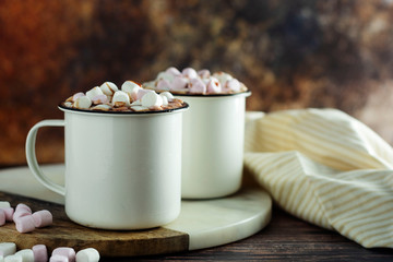 Two cups of hot chocolate, cocoa or warm drink with marshmallows on dark background