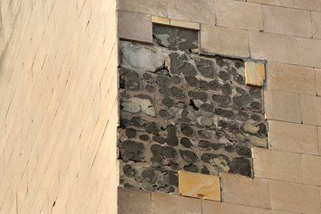 Broken and fallen off tiles on a building wall