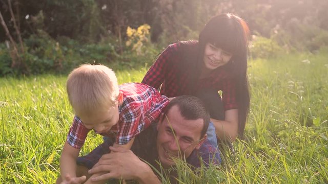 happy family teamwork outdoors have fun concept outdoors lifestyle slow motion video . mom dad and son take a photo with a smartphone in nature are sitting on the grass have fun playing .mom girl dad