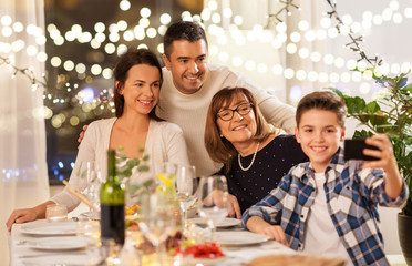 celebration, holidays and people concept - happy family having dinner party at home and taking selfie by smartphone