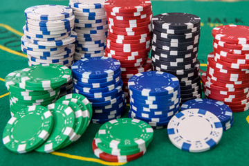 Gambling theme. Colorful casino chips on green poker table close up