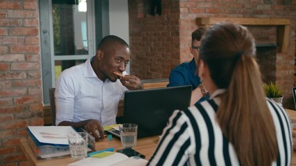 Diverse Group of People Eats Pizza in Loft Office. Business Team Enjoy Eating Lunch Together at Workplace with Laptops. Food Delivery Service and Catering at Work. 4K Gimbal Circling Medium Shot