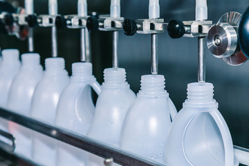 white plastic gallons or bottle on the production line of the conveyor at filling machine in the factory. selective focus. industrial and technology concept.