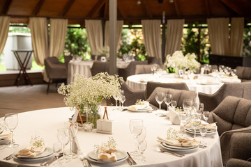 Wedding. Banquet round tables for guests with a white tablecloth. Flowers, cutlery, crockery. 