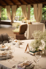 Wedding. Banquet round tables for guests with a white tablecloth. Flowers, cutlery, crockery. 