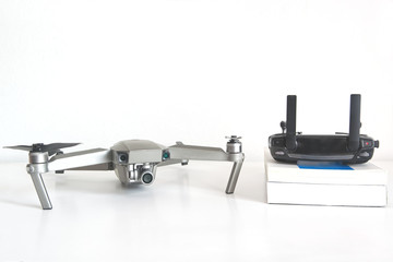 Drone and remote control next to some books in a drone pilot classroom against a white background. No people and empty copy space for Editor's text.