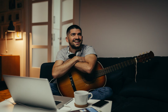 young man practice to play guitar at his home