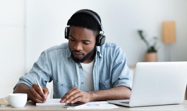 Serious african american student in headphones studying foreign language online