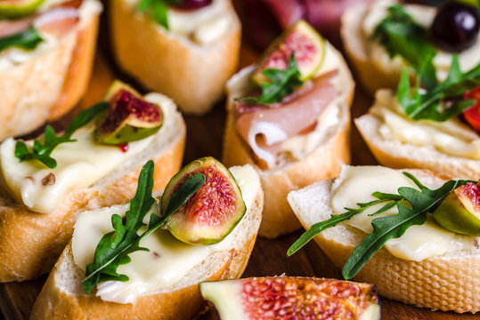 Traditional tapas from spain or italian bruschetta with cheese, meat and figs. Party food on catering platter.