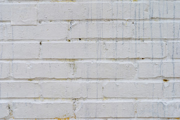 The brick wall is roughly painted white with smudges of black paint. Texture for background
