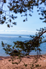 Fototapeta na wymiar Ocean kayaking near coast. Kajak fahren auf offenem Meer nahe der Küste. Blick durch Bäume auf Kajakfahrer.