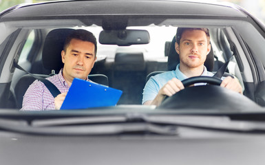 driver courses, exam and people concept - young man and driving school instructor with clipboard in...