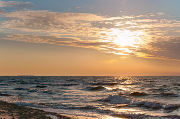 Sunset over the sea. Reflection of sunlight in the sea waves. The sky in the sunset rays.
