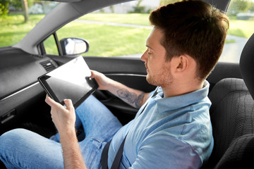 transport, technology and people concept - male passenger using tablet computer on back seat of taxi car