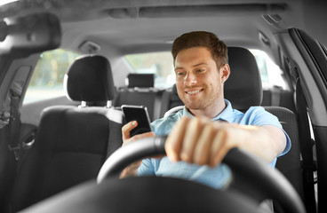transport, vehicle and technology concept - smiling man or driver driving car and using smartphone