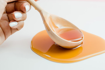 Thick honey of saturated color drips from a wooden spoon.