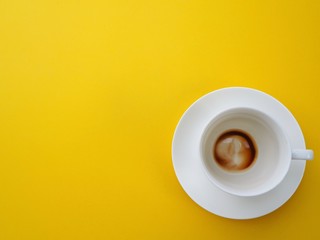 The white coffee cup is stained with coffee on a yellow background with space for putting text.