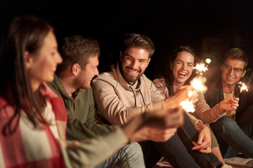 celebration, holidays and people concept - happy friends with sparklers at night outdoors
