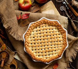 overhead shot of homemade thanksgiving warm baked apple lattice pie crust on sackcloth on rustic...