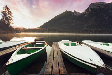 Llake hintersee in bavaria at mystic sunrise. Lake in foreground and karwendel mountains in background. Sunlight glow with view towards mount watzmann and fisherboats with wooden plank