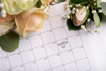 Choosing wedding date with pen writing heart on paper calendar