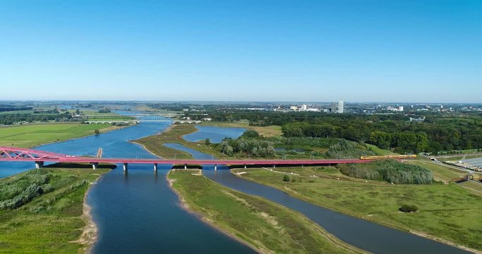 Following A Double Decker Yellow Blue Intercity Train Crossing the Hanzeboog Bridge Over the Dutch IJssel River, The Netherlands, 4K Drone Footage