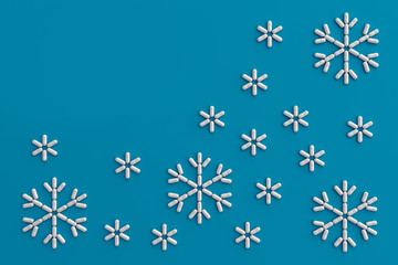 A lot of pills scattered on a blue background in the form of snowflakes . 3D illustration