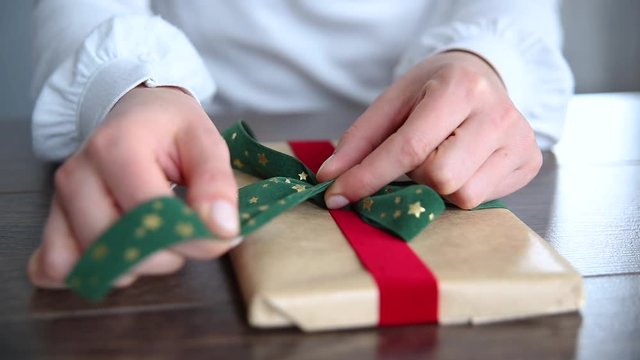Close up on woman hands packing elegant gift for Christmas, New Year