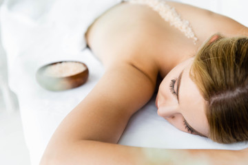 Obraz na płótnie Canvas selective focus of woman lying on massage mat with sea salt on back