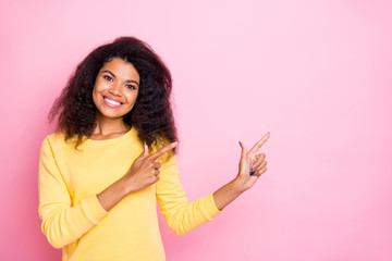 Portrait of positive african girl point index finger recommend promo true promoter show feedback choice decision wear yellow sweater isolated over pastel color background