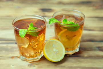 Iced tea with lemon slices and mint on wood background