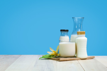 A bottle of rustic milk and glass of milk on a wooden table on a blue background