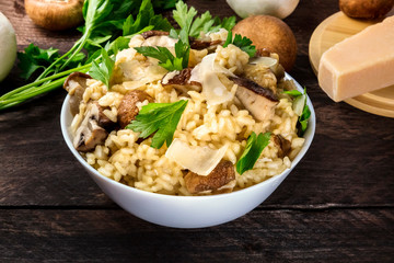 Risotto ai funghi, mushroom rice, with ingredients on a dark rustic wooden background