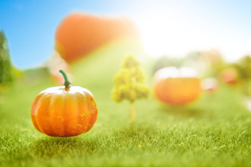 Orange plastic pumpkins on a green meadow with green grass. Macro shooting. Fairy tale.
