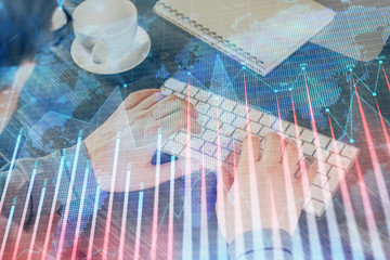 Double exposure of graph with man typing on computer in office on background. Concept of hard work.