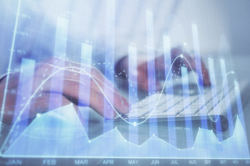 Double exposure of graph with man typing on computer in office on background. Concept of hard work.