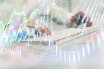 Double exposure of graph with man typing on computer in office on background. Concept of hard work. Closeup.