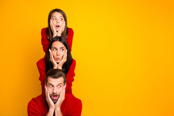 Photo of excited crazy cheerful cute funky positive family having built pyramid with their bodies astonished facial expression wearing red sweaters isolated over vivid color yellow background