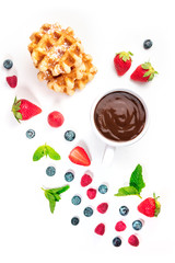 Breakfast with fresh fruit, hot chocolate, and Belgian waffles, a flat lay composition, shot from the top on a white background