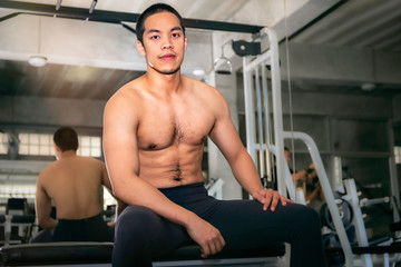 Fototapeta na wymiar Power muscular handsome Asian man strong and healthy smiling in gym after workout.