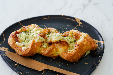 Close up bacon twist bread sticks with cheese in black dish on Mable table with copy space for text. top view delicious breakfast in morning.