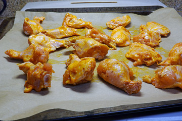Spicy raw chicken wings on baking tray, ready for oven.