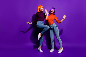 Full length body size view of two nice attractive charming cheerful excited glad girls wearing wigs dancing having fun isolated over bright vivid shine vibrant purple violet lilac color background