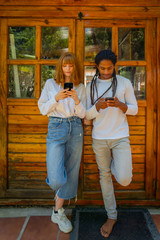 Fototapeta na wymiar Young multiracial couple using their mobile phone on a wooden background.