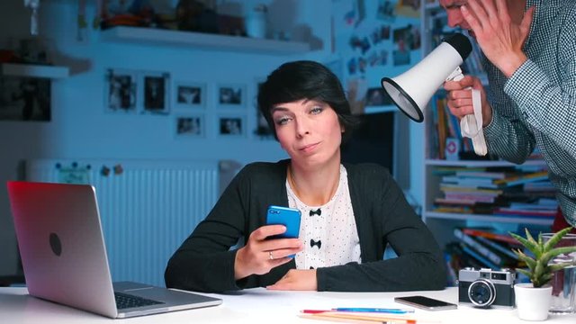 Communication problem. Young man tries to overcome a communication problem by shouting to woman through a megaphone directly into her ear, hoping to make himself heard.